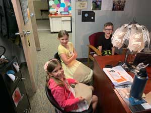 three students sitting around the principal's desk