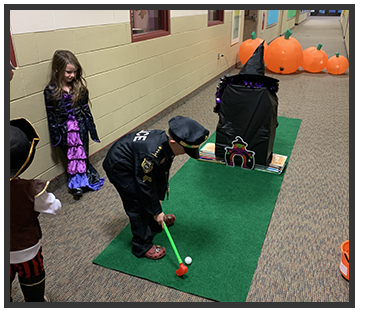 Students dressed for Halloween putting a toy golf ball into a witch house