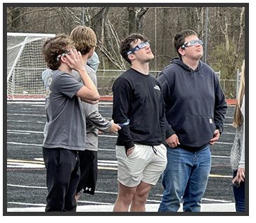 students on the track looking up with solar glasses on
