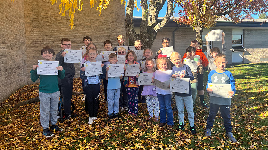 Students outside holding up their certificates of achievement