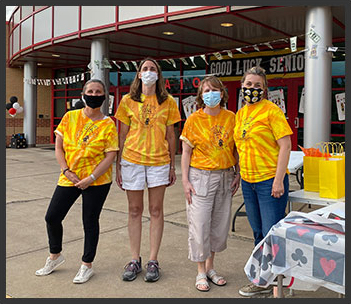 Staff with matching shirts and masks on pose together