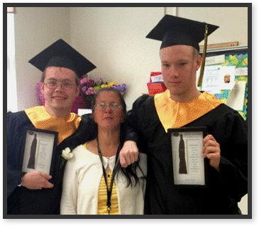 Graduates hold diplomas as they pose with a teacher
