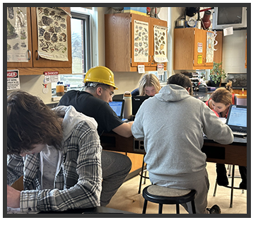 Students working on laptops on classroom tables
