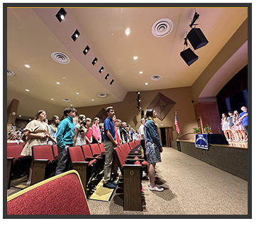 students standing in front of their seats and on stage
