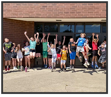Students outside jumping and waving hands