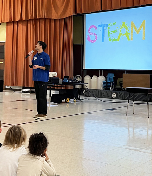 Robot assembly spokesperson speaking to students with a microphone