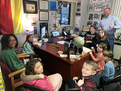 Group of happy students sitting around the principal's office