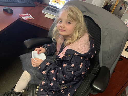 Girl sitting in principal's chair enjoying toast