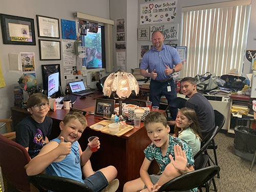 Principal with group of students enjoying toast in the principal's office