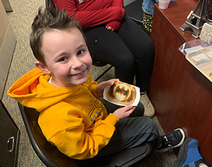 Little boy holding a piece of Batman toast during the Principal's Toast celebration