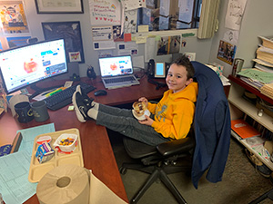 Little boy with his feet up on the principal's desk during the Principal's Toast celebration