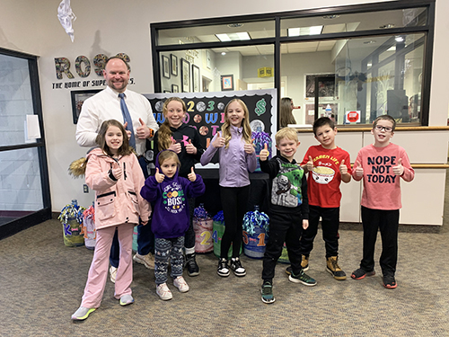 Group of happy students with the principal in the school hallway