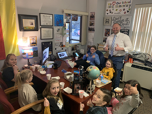 Principal and students celebrating toast to a good student