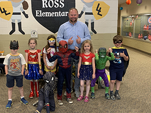 Principal posing for a picture with students dressed as superheroes.