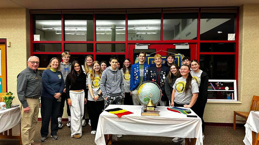 Group of happy students and adults around a table with a globe