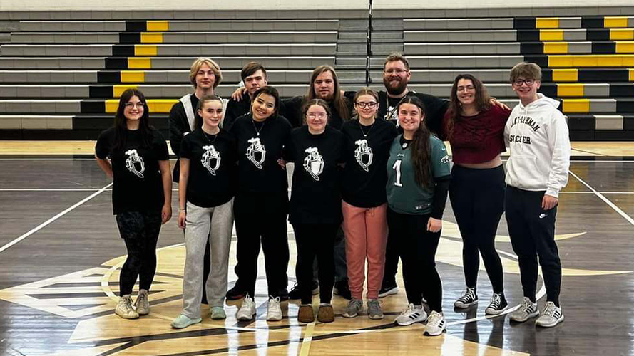 Group of students in matching black t-shirts in the gym with staff member