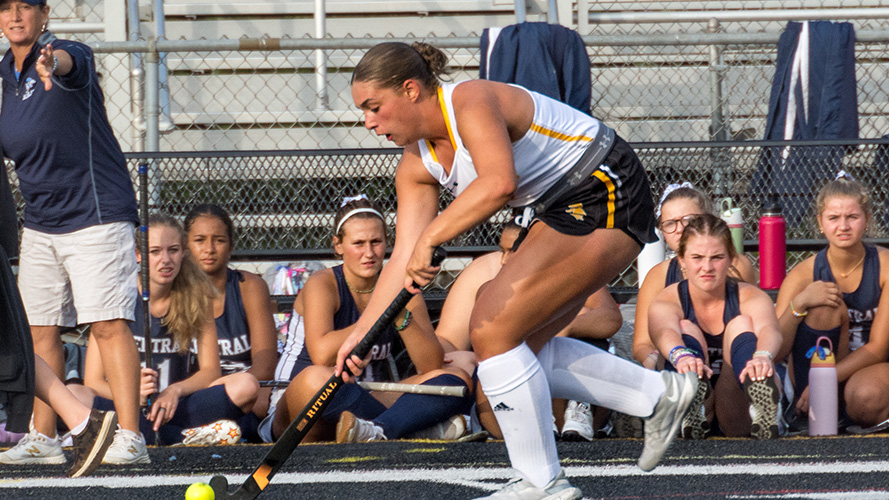 Girls field hockey team watching a player dribble the ball
